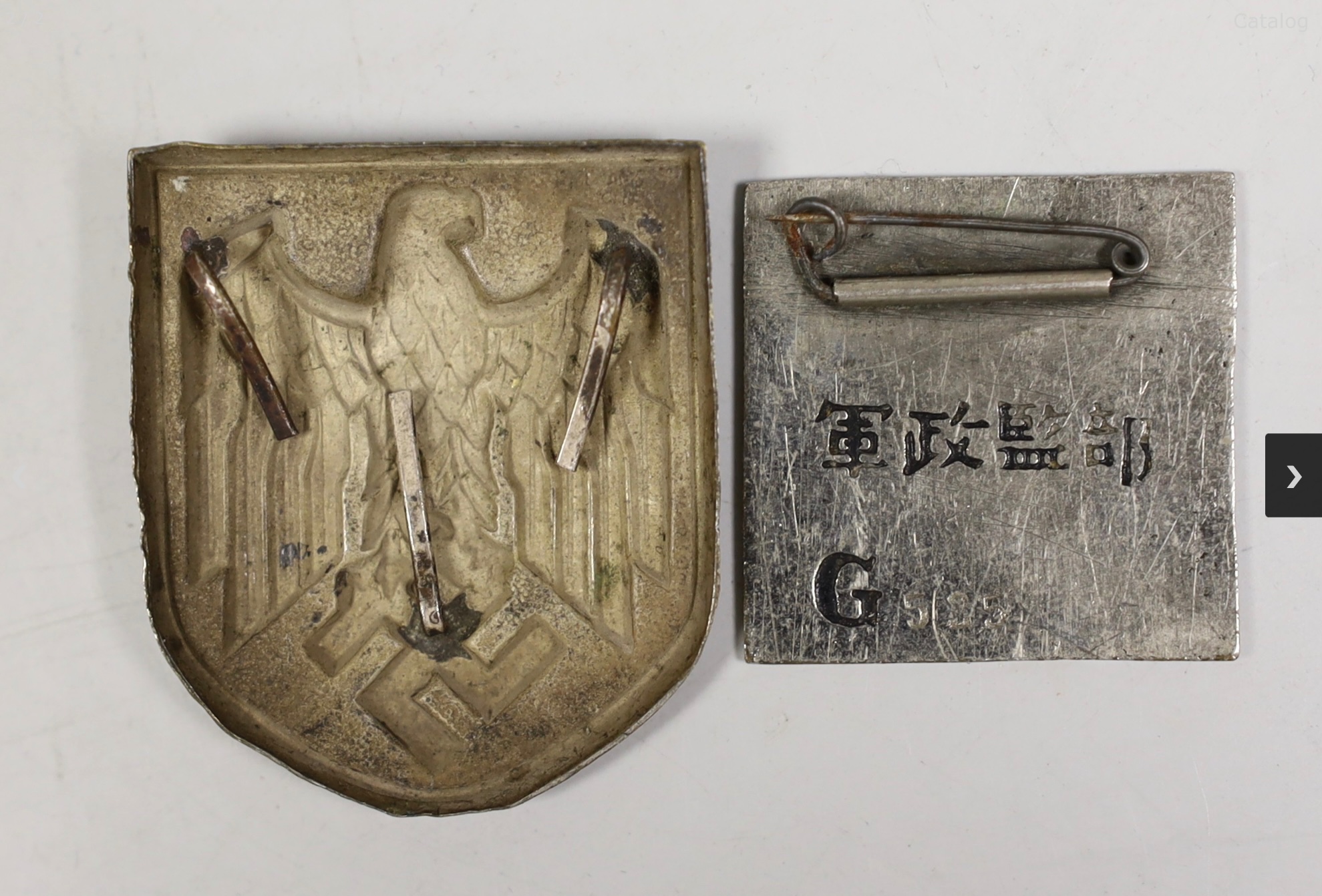 A German Third Reich Military and Political Supervision enamel badge (inscribed in Japanese?) and a kriegsmarine pith helmet shield badge
